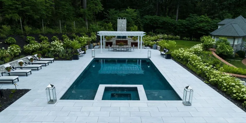 rectangular inground pool with square spa and large pool deck, large grand fireplace with dining sitting area